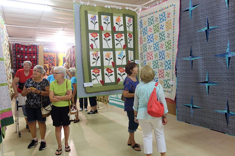 Visitors browse quilts Saturday at the second annual Rooster Creek Quilt Show in Holts Summit. 