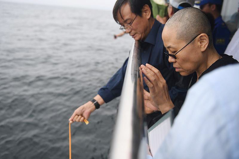 In this photo provided by the Shenyang Municipal Information Office, Liu Xia, the wife of imprisoned Chinese Nobel Peace Prize laureate Liu Xiaobo, watches as Liu's ashes are buried at sea off the coast of Dalian in northeastern China's Liaoning Province, Saturday, July 15, 2017. China cremated the body of Liu on Saturday, July 15, 2017, who died this week after a battle with liver cancer amid international criticism of Beijing for not letting him travel abroad as he had wished. (Shenyang Municipal Information Office via AP)