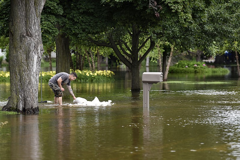 A man picks up sandbags to reinforce the barrier he built to keep the flood water from reaching his house Friday, July 14, 2017, in Gurnee, Ill. Illinois officials said Friday that several thousand buildings have been affected by "unprecedented" flooding north of Chicago, and the damage is expected to worsen this weekend as water flows down rivers into the state from Wisconsin. (AP Photo/G-Jun Yam)