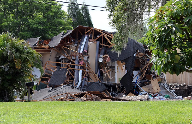 Debris is strewn about from a partially collapsed home in Land O' Lakes, Fla. on Friday, July 14, 2017.A sinkhole that started out the size of a small swimming pool and continued to grow has swallowed a home in Florida and severely damaged another. (Alessandra da Pra/Tampa Bay Times via AP)