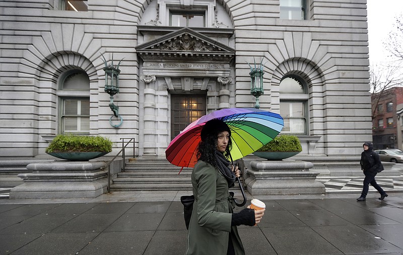FILE - In this Feb. 9, 2017, file photo, Monica Fine, center, walks past the 9th U.S. Circuit Court of Appeals building in San Francisco. The nation's largest federal court circuit is set for its annual meeting after a contentious six months that has seen its judges repeatedly clash with President Donald Trump, and its agenda is not shying away from topics that have stoked the president's ire. Immigration, the news media and meddling in the U.S. election are among the subjects that will be discussed at the 9th Circuit's four-day conference in San Francisco that begins on Monday, July 17, 2017. (AP Photo/Marcio Jose Sanchez, File)
