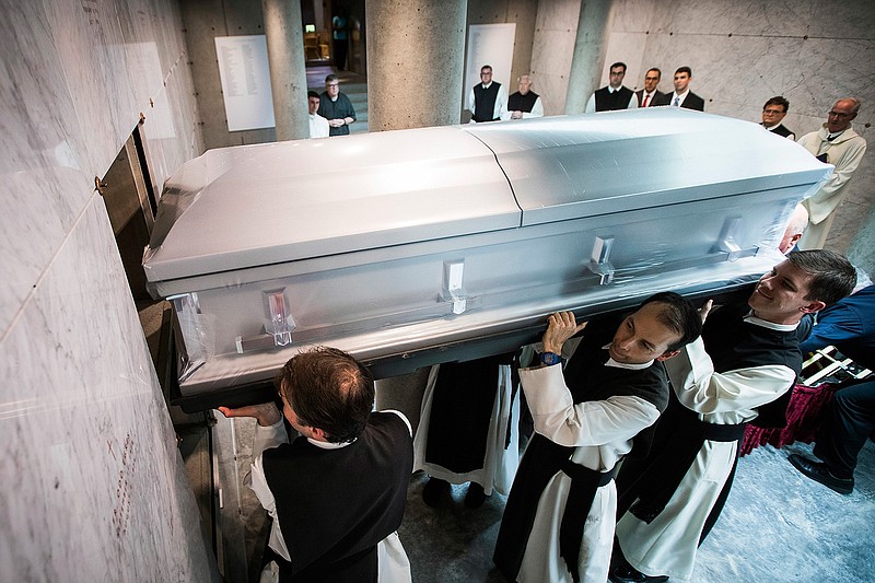 In this June 29, 2017 photo, the remains of Rev. Rudolph Zimanyi are lifted into crypt by monks at the Cistercian Abbey during reinterment services in Irving, Texas.   For years, Cistercian Abbey Our Lady of Dallas had no cemetery or mausoleum on its Irving campus, so the monks who lived and died there were buried several miles away at Calvary Hill Cemetery. In June  the abbey dedicated a new, $1.5 million crypt, built largely with donations from alumni of the all-male Cistercian Preparatory School. 