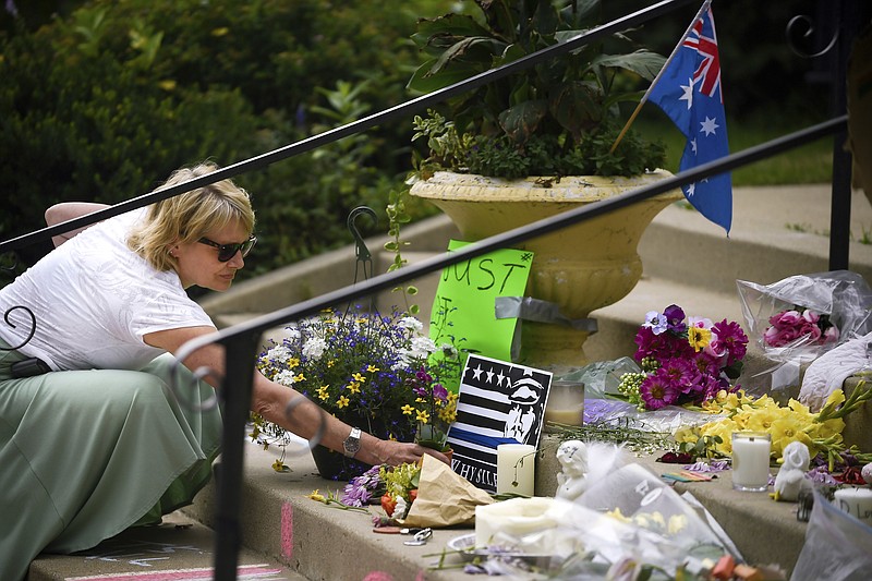 In this Wednesday, July 19, 2017 photo, a Robyn Traxler, a lifelong resident of the Linden Hills neighborhood, placed flowers at the memorial for Justine Damond on the steps of the Lake Harriet Spiritual Community church in south Minneapolis. The family of Damond, an Australian woman shot to death by a Minneapolis police officer, has hired an attorney who represented the family of black motorist Philando Castile, who was also slain by a Minnesota police officer. (Aaron Lavinsky/Star Tribune via AP)
