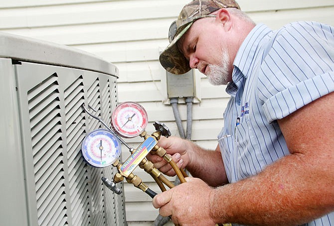 Arron Lane performs routine maintenance on an air conditioning unit Wednesday at a house in Jefferson City. Lane has been with Aire Serv for more than a year and said the summer is one of his busiest seasons.