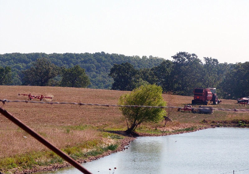 This August 2012 file photo shows hay mowing and baling equipment sitting in a farm field on a Miller County farm near a livestock pond.