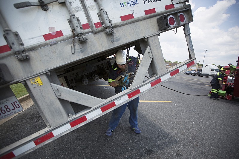 Tommy Wacasey with Neeley's Towing hooks up to a tractor-trailer that nearly tipped onto its side and went into the drainage ditch between the Walmart Supercenter and Schlotzsky's on Thursday in Texarkana, Ark. The driver of the 18-wheeler left the trailer overnight, and when he returned, another vehicle was parked in front of the trailer, blocking him from hooking onto the trailer straight on. The driver tried to back up at an angle but hit the box trailer, knocking it into the drainage ditch. No one was injured in the incident, but the trailer was heavily damaged. The loaded trailer was originally on its way to Laredo, Texas. 
