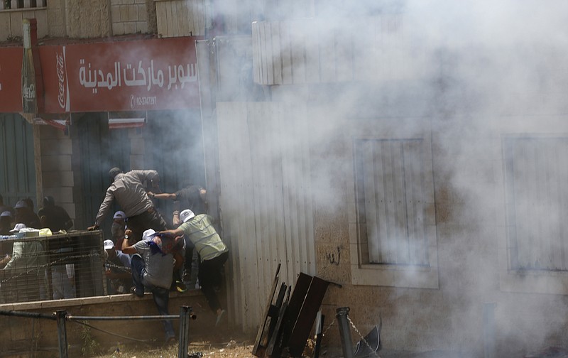 Palestinians run for cover from tear gas shot by Israeli soldiers during clashes in the West Bank city of Bethlehem, Friday, July 21, 2017. Israel police severely restricted Muslim access to a contested shrine in Jerusalem's Old City on Friday to prevent protests over the installation of metal detectors at the holy site.(AP Photo/Nasser Shiyoukhi)
