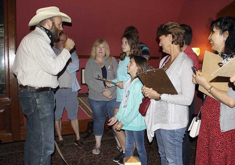 In this July 14, 2017 photo, actor Dan Russell, left, portraying the character Arkansas from Mark Twain's book Roughing it, responds to a question from 10-year-old Emma Connell, center, of Arizona during a "Clue" tour at the Mark Twain House in Hartford, Conn. The tour allows visitors to interact with Twain characters while playing a live-action version of the board game. (AP Photo/Pat Eaton-Robb)