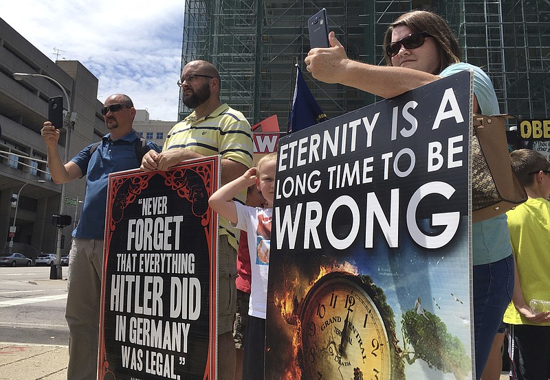 In this Wednesday, July 19, 2017, abortion opponents with a group called Operation Save America gather during a rally in downtown Louisville, Ky.  A federal judge issued an order Friday, July 21, 2017, to keep protesters away from a "buffer zone" outside Kentucky's only abortion clinic, which is targeted by a national anti-abortion group.  U.S. District Judge David J. Hale issued a temporary restraining order sought by federal prosecutors in a pre-emptive move ahead of vigils by Operation Save America. The order is aimed at preventing abortion foes from impeding access to EMW Women's Surgical Center in Louisville. . (AP Photo/Dylan Lovan)