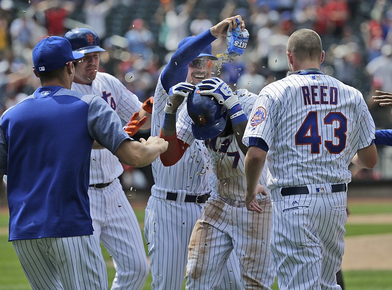 New York Mets' Jose Reyes, center, is mobbed by teammates after hitting a walk-off RBI single during the ninth inning of a baseball game Thursday against the St. Louis Cardinals at Citi Field in New York. The Mets defeated the Cardinals, 3-2. 