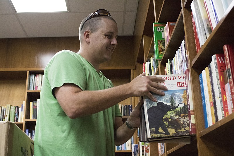 Zach Flanagan puts books on the shelves on Friday in preparation of the open house and ribbon cutting at the new Randy Sams' Outreach Shelter administration building at 11 a.m. today. The ceremony will begin at 10 a.m. at the shelter, 402 Oak St., Texarkana, Texas, before moving to the new building.