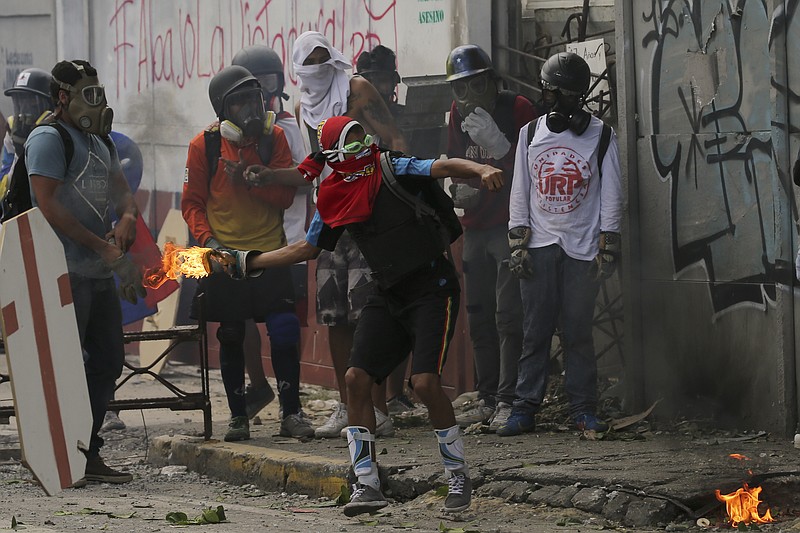 An anti-government protester winds up holding a homemade petrol bomb during clashes with security forces preventing a march to the Supreme Court opposing President Nicolas Maduro's plan to rewrite the constitution, in Caracas, Venezuela, Saturday, July 22, 2017. Venezuelan authorities have routinely responded with tear gas and rubber bullets to nearly four months of street protests, during which at least 97 people have died in the unrest. (AP Photo/Fernando Llano)