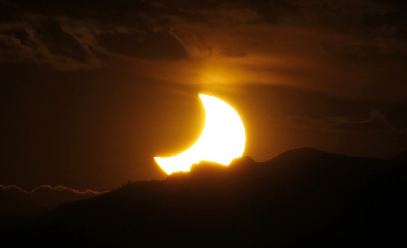 FILE - In this May 20, 2012, file photo, the annular solar eclipse is seen as the sun sets behind the Rocky Mountains from downtown Denver. The solar eclipse that is cutting a diagonal path across the U.S. next month is a boon for Missouri tourism. Some towns will have more visitors than residents on Aug. 21, 2017. Hotels and campsites are sold out as some communities are preparing for unparalleled numbers of visitors, all to observe about two minutes of near-darkness at the height of the day. (AP Photo/David Zalubowski, File)