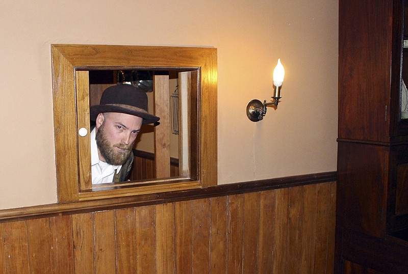 Actor Allan Smith, portraying the Mark Twain character Muff Potter, peers at visitors July 14 from a pass-through in the kitchen during a "Clue" tour of the Mark Twain House in Hartford, Conn. The tour allows visitors to interact with Twain characters while playing a live-action version of the board game.