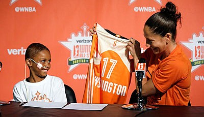 Storm guard Sue Bird (right) holds up a jersey for Eniyah Washington, 6, after Bird signed the youngster to a WNBA All-Star basketball "contract" Friday for the Western Conference team through the Austen Everett Foundation in Seattle.