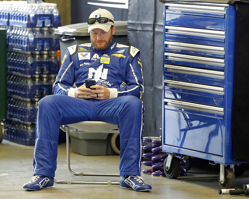 Race driver driver Dale Earnhardt Jr. looks at his phone before a practice session for the NASCAR auto race at Indianapolis Motor Speedway, in Indianapolis Saturday, July 22, 2017. 
