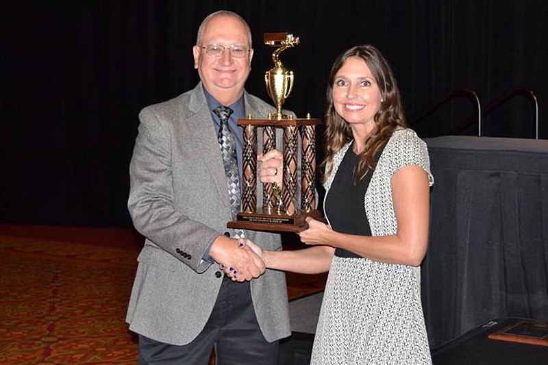 Robin Sams, left, receives the first-place three-axle division trophy from Sarah Sheets with the Arkansas Trucking Association. Sams participated in the Arkansas Truck Driving Championship held earlier in July in Rogers, Ark.