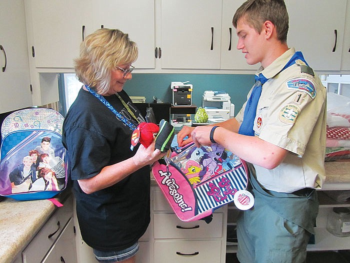At right, Malachi Saint, 15, and his mother, Deeann, place items into backpacks to be given to local foster children at the Central Missouri Foster Care and Adoption Association. Malachi, who went through the foster care system, is using his Eagle Scout project to improve the lives of other foster children.