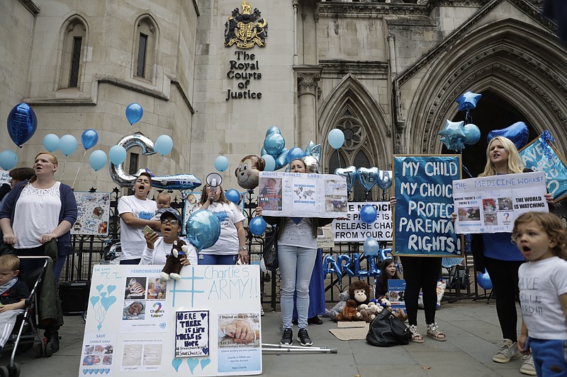 Supporters of critically ill baby Charlie Gard shout and hold placards before his parents Connie Yates and Chris Gard arrive Monday at the High Court in London. The parents of the 11-month old, who has a rare genetic condition and brain damage, dropped their effort to seek permission to take the child to the United States for medical treatment.
