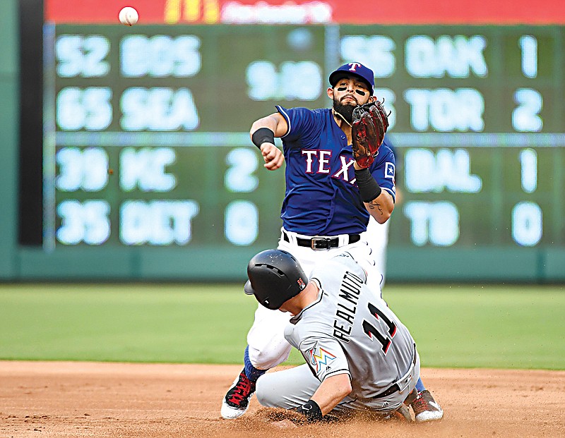 Texas Rangers second baseman Rougned Odor, top, turns a double play over Miami Marlins' J.T. Realmuto (11) in the first inning Monday in Arlington, Texas.