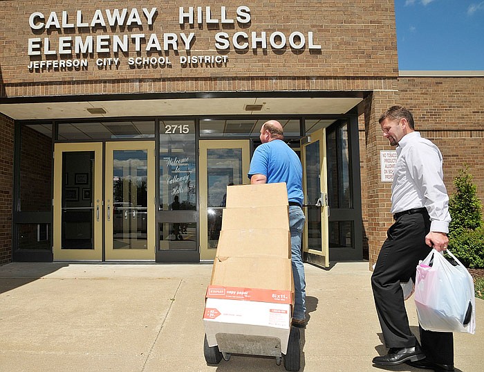 In this Aug. 12, 2014 file photo, Scott Moore and John Elliston, right, carry in school supplies to Callaway Hills Elementary School. A project is in the works to switch the school away from a lagoon-based sewer system. 