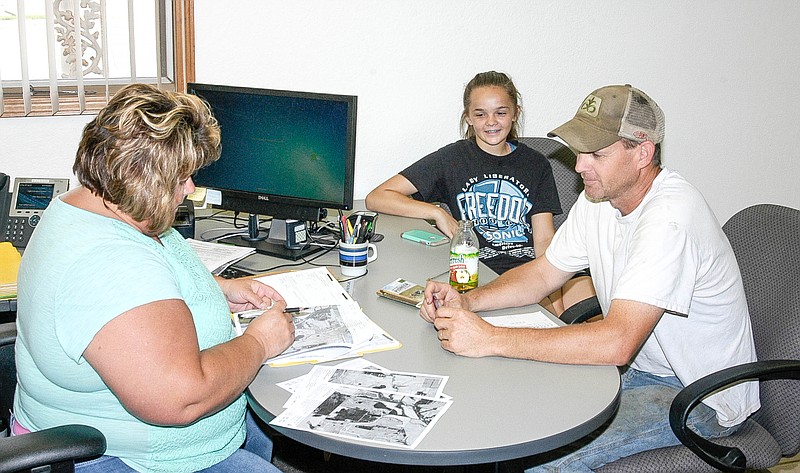 <p>Democrat photo / David A. Wilson</p><p>At the Moniteau County Farm Service Agency office on Buchanan Street, Tammy Bleich, left takes the Crop Report of Doug Porter, as his daughter Tristan watches the procedure.</p>