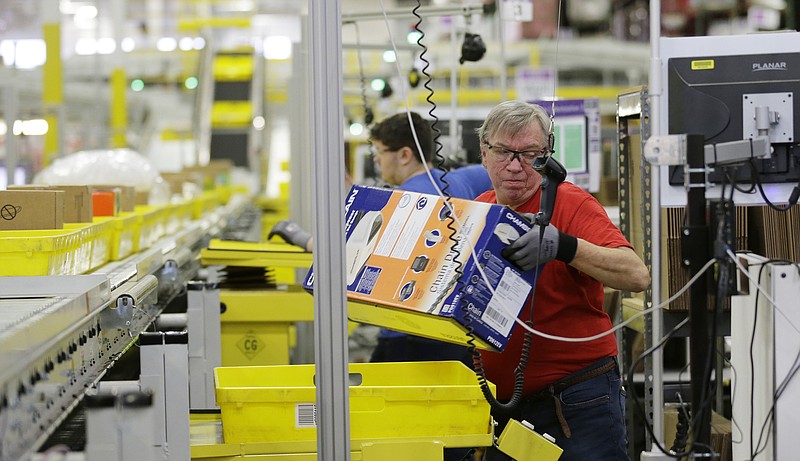 FILE - In this Monday, Nov. 30, 2015, file photo, Mark Oldenburg processes outgoing orders at Amazon.com's fulfillment center in DuPont, Wash. On Wednesday, July 26, 2017, Amazon said that it’s looking to fill more than 50,000 positions across its U.S. fulfillment network. It’s planning to make thousands of job offers on the spot during its first Jobs Day on Aug. 2, where potential employees will have a chance to see what it’s like to work at Amazon by visiting one of 10 participating fulfillment centers. (AP Photo/Ted S. Warren, File)