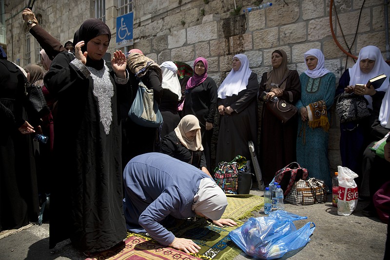 Palestinian women pray at the Lion's Gate following an appeal from clerics to pray in the streets instead of the Al Aqsa Mosque compound, in Jerusalem's Old City, Tuesday, July 25, 2017. Dozens of Muslims have prayed in the street outside a major Jerusalem shrine, heeding a call by clerics not to enter the site until a dispute with Israel over security arrangements is settled. This comes after Israel removed metal detectors earlier on Tuesday. (AP Photo/Oded Balilty)