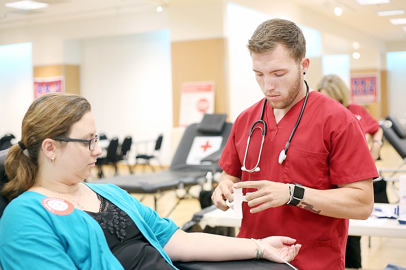 Melinda Cardone, left, prepares to donate blood Tuesday, July 25, 2017, with the help of Cole Nunn during a blood drive at Capital Mall in Jefferson City. This event was hosted by the American Red Cross in honor of Hudson Lee, a local teen who survived leukemia due to blood donors.