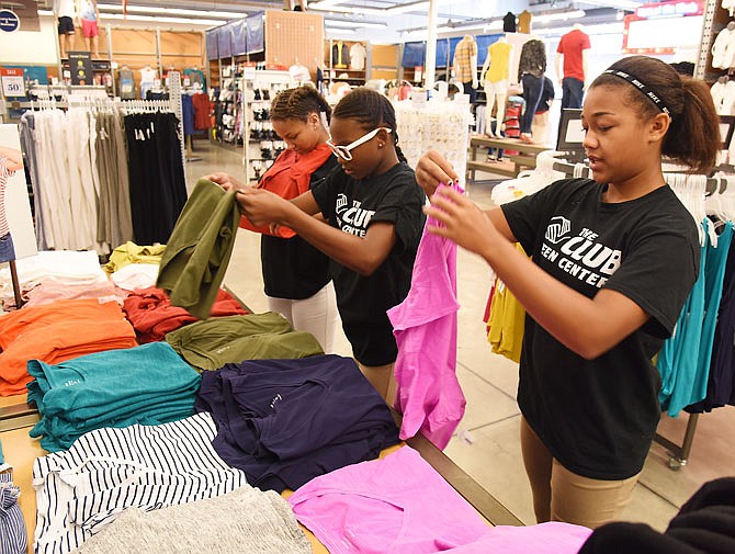  From right, Rylea Sanning, 13, Emmarie Graham, 12, and Delaney White, fold and organize women's shirts Tuesday for a display at Old Navy. About a dozen students from the Boys & Girls Club spent part of their morning at the store learning what it's like to work in retail. 