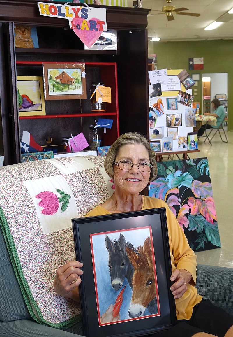 Holly Anson holds a painting of the two donkeys she found in a local field. She thought they needed their portraits made.
