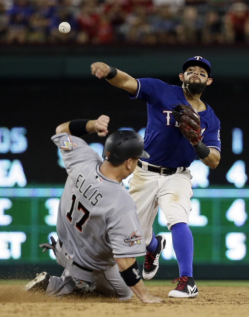 Texas Rangers second baseman Rougned Odor, top, throws to first to complete the double play after forcing Miami Marlins' A.J. Ellis (17) at second in the sixth inning of a baseball game Tuesday in Arlington, Texas. The Marlins' Mike Aviles was out at first on the play. 
