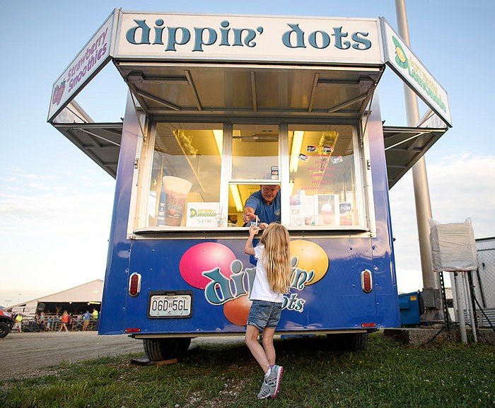 Adyison Wykes, 5, reaches up to grab a cup of cool, sweet relief after stopping by the Dippin'
Dots trailer during last year's Jefferson City Jaycees Cole County Fair.