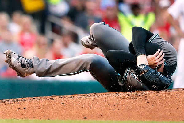 Diamondbacks starting pitcher Robbie Ray falls to the ground after being hit on the head by a ball hit by Luke Voit of the Cardinals during the second inning of Friday night's game at Busch Stadium.