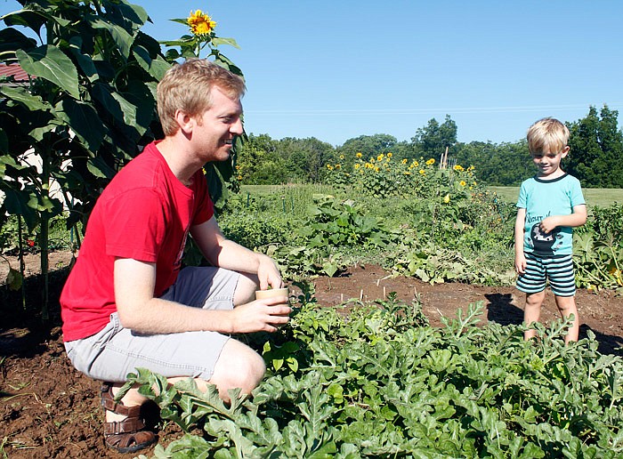 Jacob Luecke and his 6-year-old son, Brynn, check their watermelon plants Saturday, July 29, 2017 at
the community garden at Wesley United Methodist Church. The Luecke family is not able to grow
plants in their own yard because of how many trees they have shading the area.