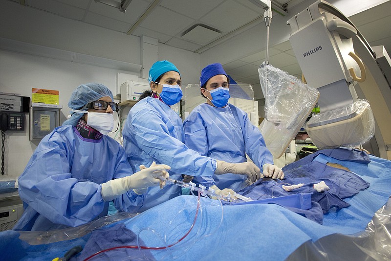 Dr. Annapoorna Kini, center, performs a non-emergency angioplasty at Mount Sinai Hospital in New York. Through a blood vessel in the groin, she guides a tube to a blockage in the heart. She inflates a tiny balloon to flatten the clog, and leaves behind a mesh tube called a stent to prop the artery open.