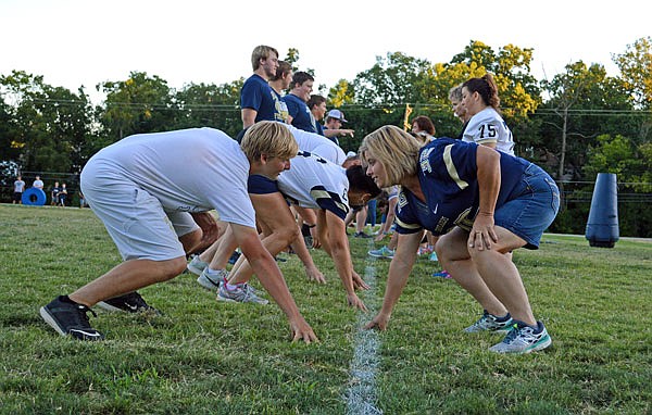 Helias football players show their moms how to get into a three-point stance during Mom's Night at the Helias practice field Friday night.