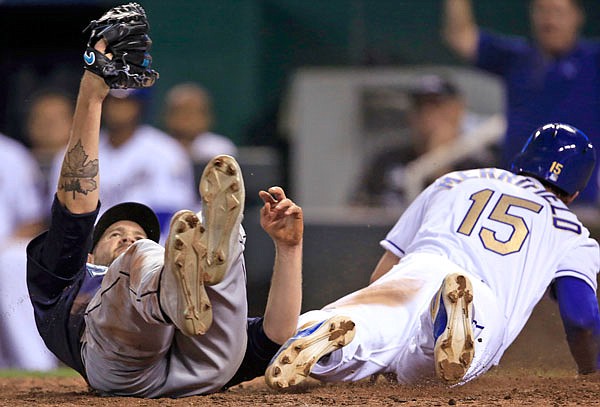 Royals second baseman Whit Merrifield (right) scores on a wild pitch by Mariners pitcher James Paxton (left) during the sixth inning of Friday night's game at Kauffman Stadium in Kansas City.