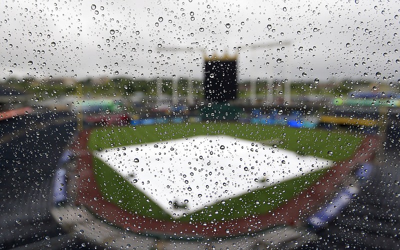 The tarp and playing surface are seen through raindrops on a press box window at Kauffman Stadium in Kansas City, Mo., before a baseball game between the Kansas City Royals and the Seattle Mariners Saturday, Aug. 5, 2017 which was eventually postponed until Sunday.