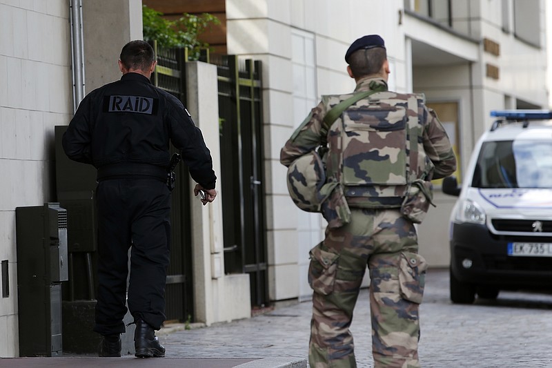 French soldiers walk near the scene where French soldiers were hit and injured by a vehicle in the western Paris suburb of Levallois-Perret near Paris, France, Wednesday, Aug. 9, 2017. French police are searching for a driver who slammed his BMW into a group of soldiers, injuring six of them in an apparent ambush before speeding away, officials said. The incident in Levallois, northwest of Paris, is the latest of several attacks targeting security forces in France.(AP Photo/Kamil Zihnioglu)