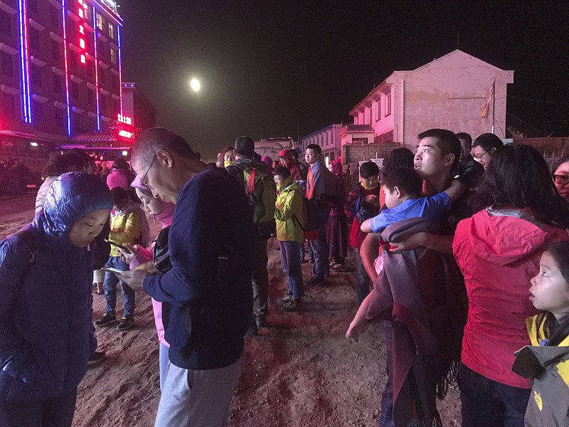 Tourists stand outside a hotel Tuesday after being evacuated following a strong earthquake in Ruo'ergai in southwestern China's Sichuan province. The mountainous region shaken by the quake is near a famous national park.