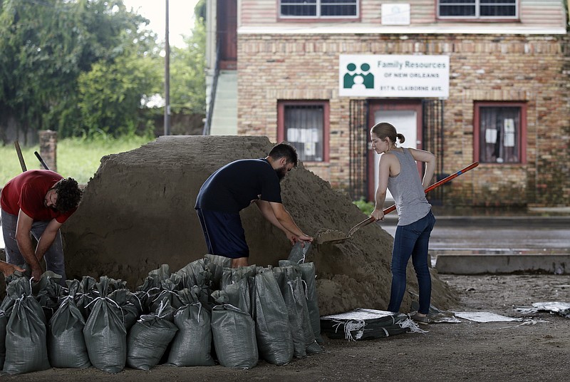 Andrea Dube, right, and John Flemming fill sandbags as a precaution for the potential of more flooding from rain storms, in New Orleans, Friday, Aug. 11, 2017. With debris from last weekend's flash flood still piled up on sidewalks and their city under a state of emergency, New Orleans residents looked ahead warily on Friday to the prospect of more rain to tax the city's malfunctioning pump system. (AP Photo/Gerald Herbert)
