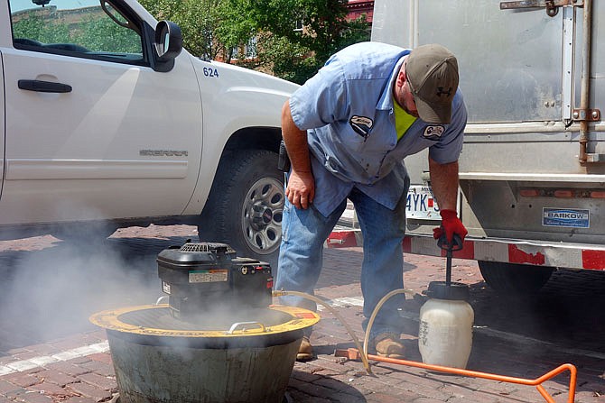 Michael Cunningham, crew leader for the Fulton wastewater department, pumps smoke-creating chemicals into a blower, then into the city's stormwater system. A drone overhead, operated by a team from Burns and McDonnell engineering firm, looked for smoke escaping from downtown rooftops, indicating cracks in the system.