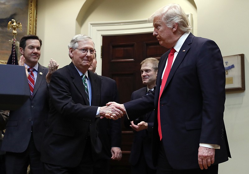 FILE - In this Feb. 16, 2017, file photo, President Donald Trump shakes hands with Senate Majority Leader Mitch McConnell of Ky., during a ceremony in the Roosevelt Room of the White House in Washington. Trump’s attacks on McConnell come at the worst possible time, if the president’s goal is actually to accomplish the agenda on health care, infrastructure and taxes he’s goading his GOP ally to pass. Behind from left are Rep. Evan Jenkins, R-W.Va., and Rep. Jim Jordan, R-Ohio.(AP Photo/Carolyn Kaster, File)