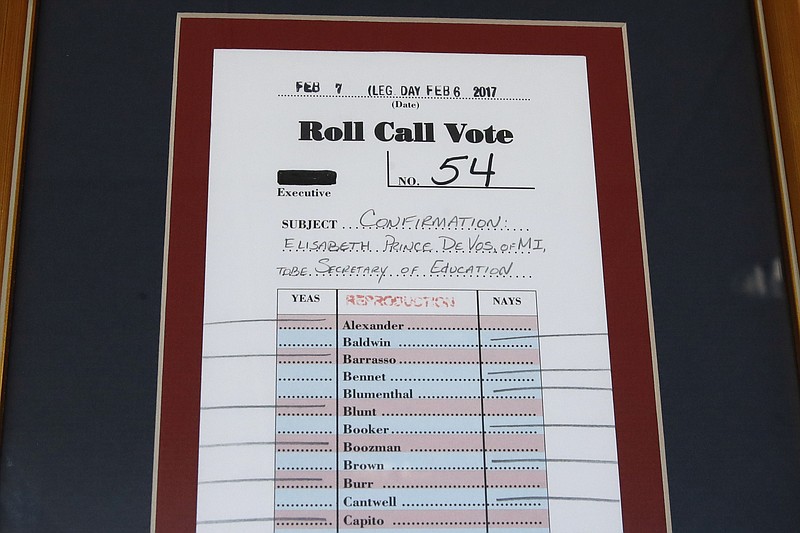 In this Aug. 9, 2017, photo, a framed reproduction of the roll call vote in Congress to approve Betsy DeVos as education secretary hangs on a wall in her office at the Education Department in Washington. It’s been six months since her bruising Senate confirmation battle, and DeVos remains highly divisive. (AP Photo/Jacquelyn Martin)