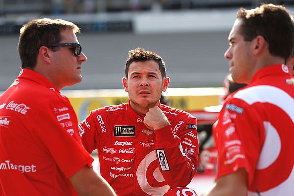 Kyle Larson talks with crew members Friday after qualifying for the NASCAR Cup Series race in Brooklyn, Mich.