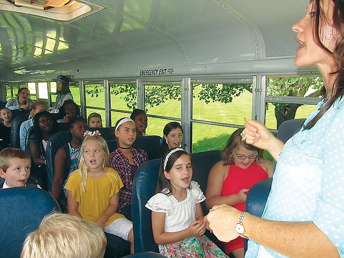 Angel Marks, right, leads children in song on the Central Baptist Church bus on Sunday. The bus travels to homes on Saturday to pass out snacks and see who plans to attend church on Sunday, then picks up people to bring to church and back home on Sunday. Marks is a youth director at the church, which celebrated its 30th anniversary Sunday.