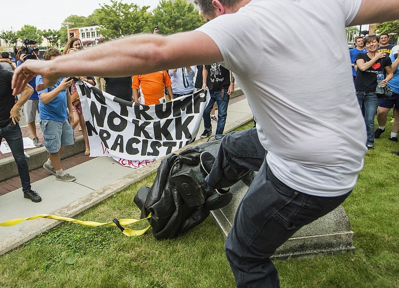 <p>A protester kicks the toppled statue of a Confederate soldier after it was pulled down Monday in Durham, North Carolina. Activists on Monday evening used a rope to pull down the monument outside a Durham courthouse.</p>