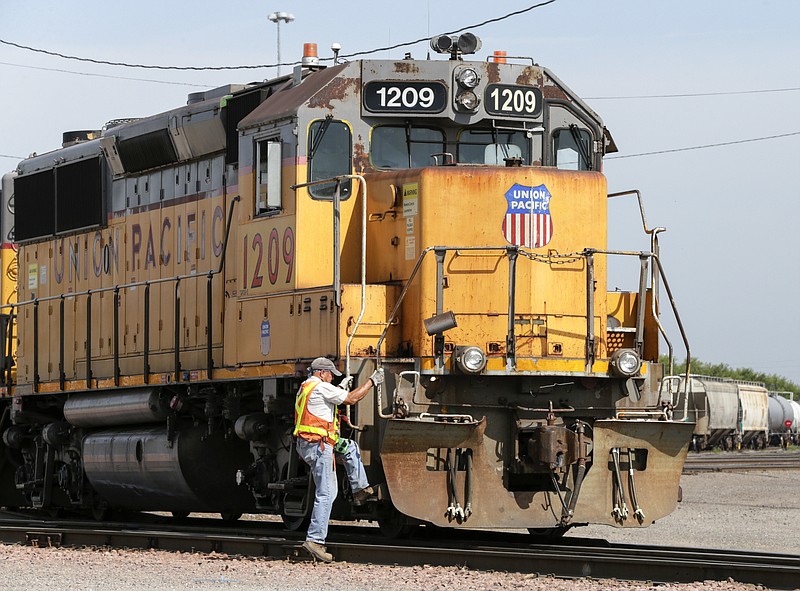 FILE - In this Thursday, July 20, 2017, file photo, a Union Pacific employee climbs on board a locomotive in a rail yard in Council Bluffs, Iowa. Union Pacific is laying off 500 managers and 250 other workers to reduce costs and eliminate about 8 percent of the railroad’s managers. The railroad told the affected workers Wednesday, Aug. 16, 2017, that their jobs will be eliminated by mid-September. (AP Photo/Nati Harnik, File)