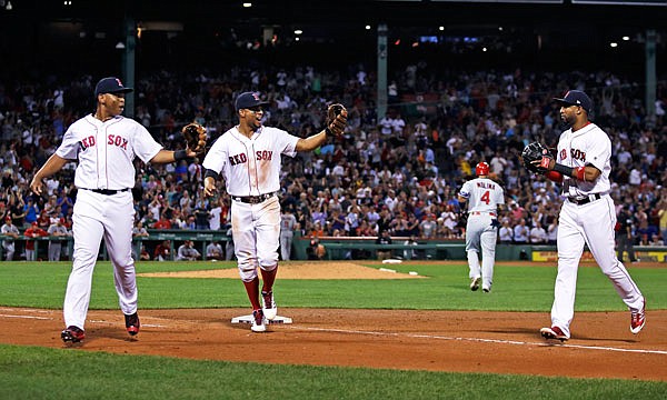 (From left), Red Sox third baseman Rafael Devers, shortstop Xander Bogaerts and second baseman Eduardo Nunez celebrate after turning a triple play on a ground out by Yadier Molina of the Cardinals during the fourth inning of Tuesday night's game in Boston.